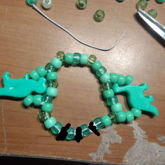 green bracelet with dinosaur charms and censored letter 
      beads