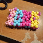 kandi cuff made out of pale pink, blue, 
      yellow, and magenta beads
